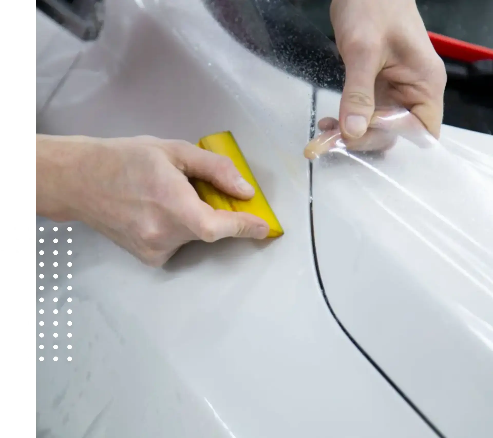 Hands applying clear protective film to car